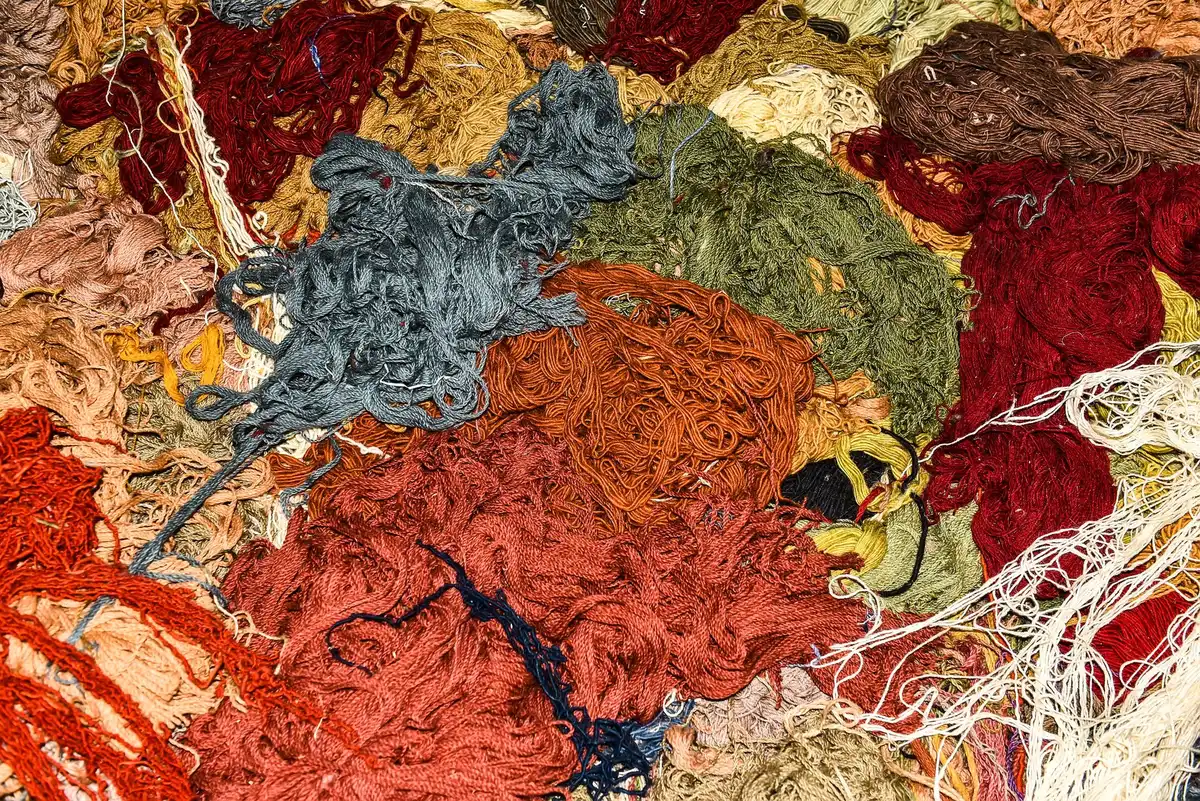 Mains créant des touffes de fil coloré sur une toile tendue avec une technique de tufting artisanal
