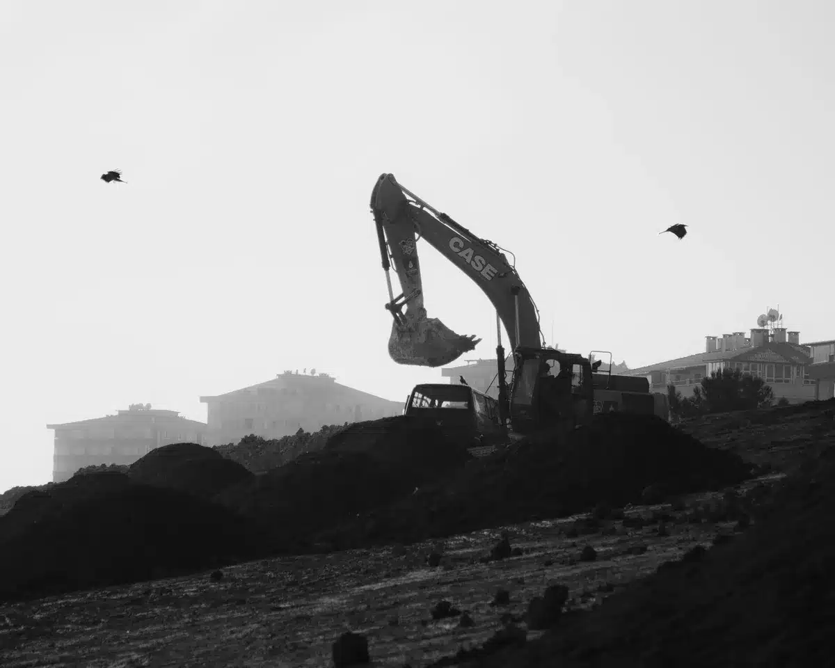 Vue aérienne d'un chantier de construction de piscine avec excavation, matériaux et plans
