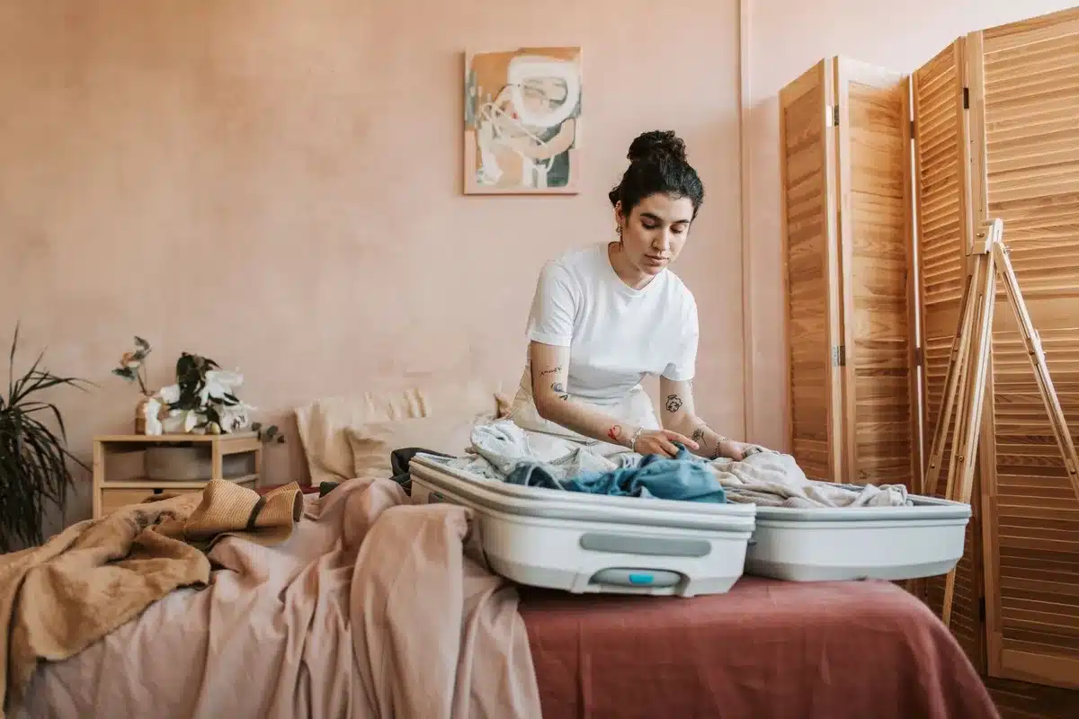 Valise ouverte avec vêtements pliés, chaussures confortables et produits de soin disposés sur un lit