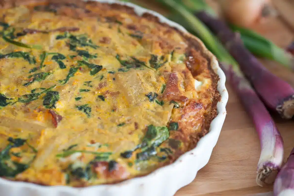 Montage de lasagnes avec couches de légumes printaniers et sauce crémeuse dans un plat de cuisson