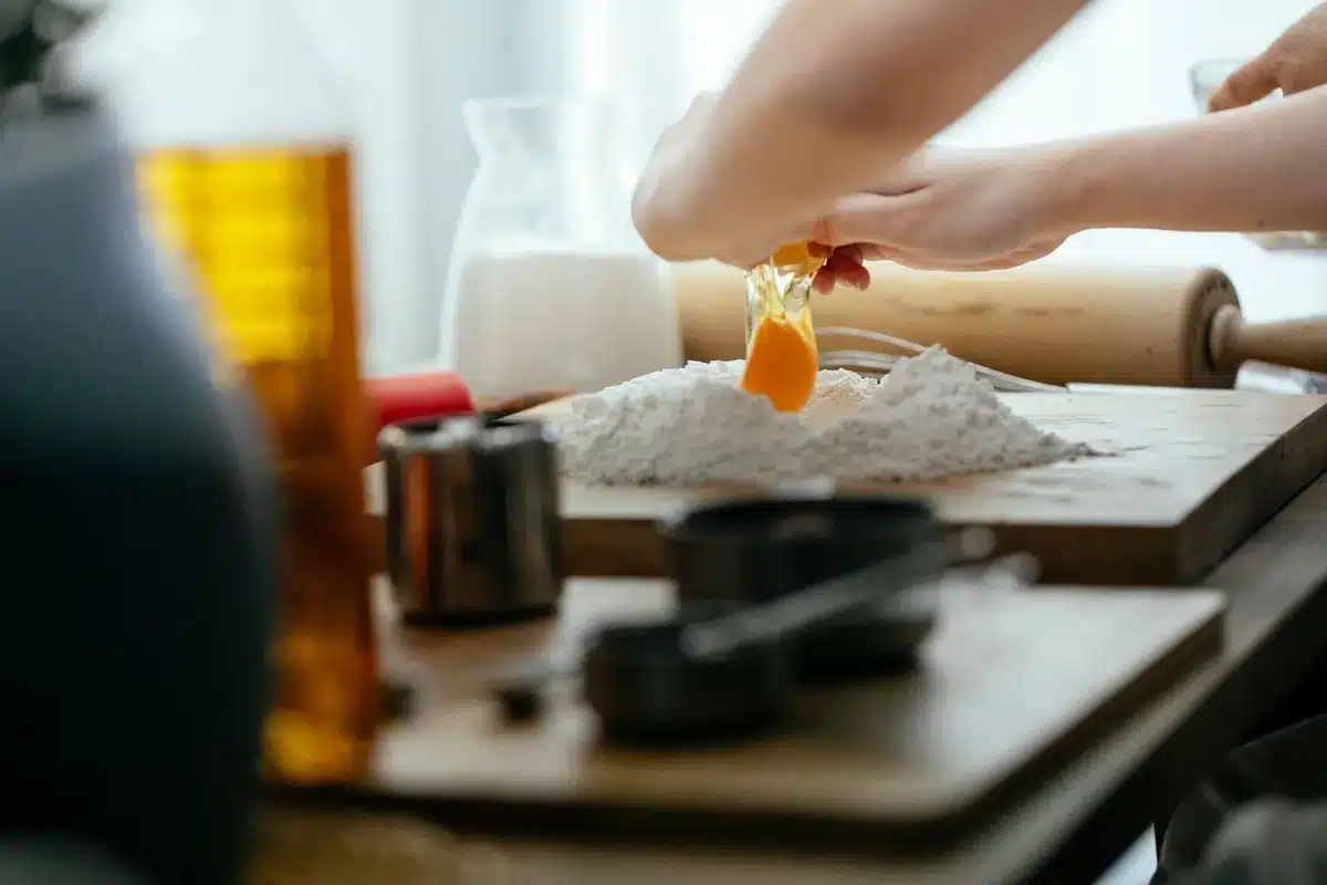 Mains pétrissant une pâte sucrée sur un plan de travail fariné avec ustensiles de pâtisserie