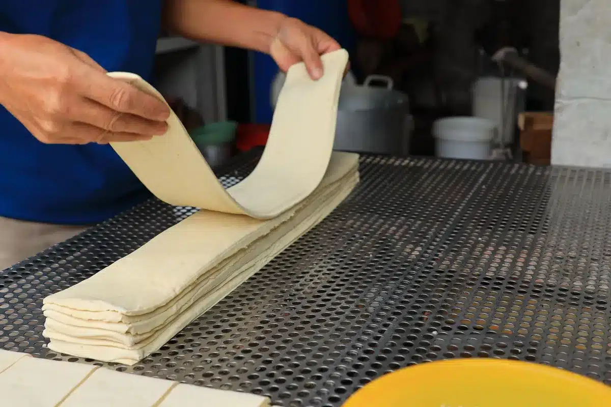 Pâte feuilletée en cours de laminage avec beurre visible entre les couches