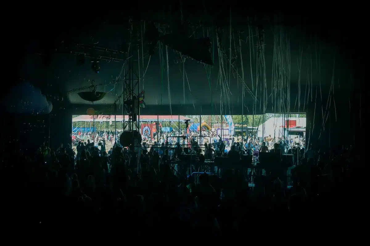 Foule de festivaliers dansant sous les lumières colorées d'une scène en plein air