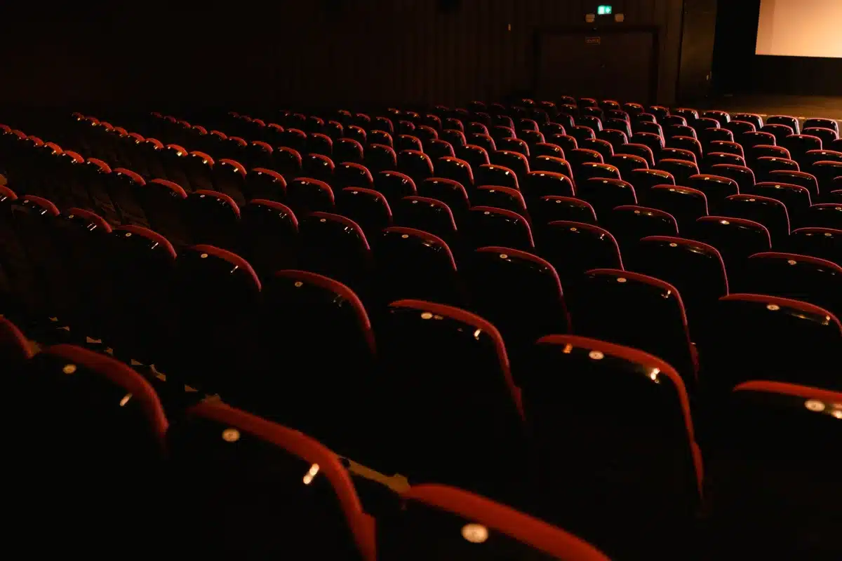 Rangées de sièges de cinéma vides dans une salle sombre, prêts pour la projection