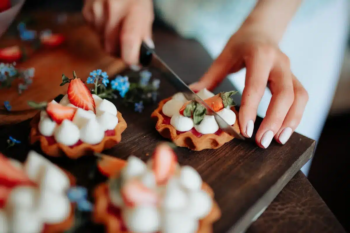 Mains préparant une tarte salée avec tomates, moutarde et thon sur pâte feuilletée