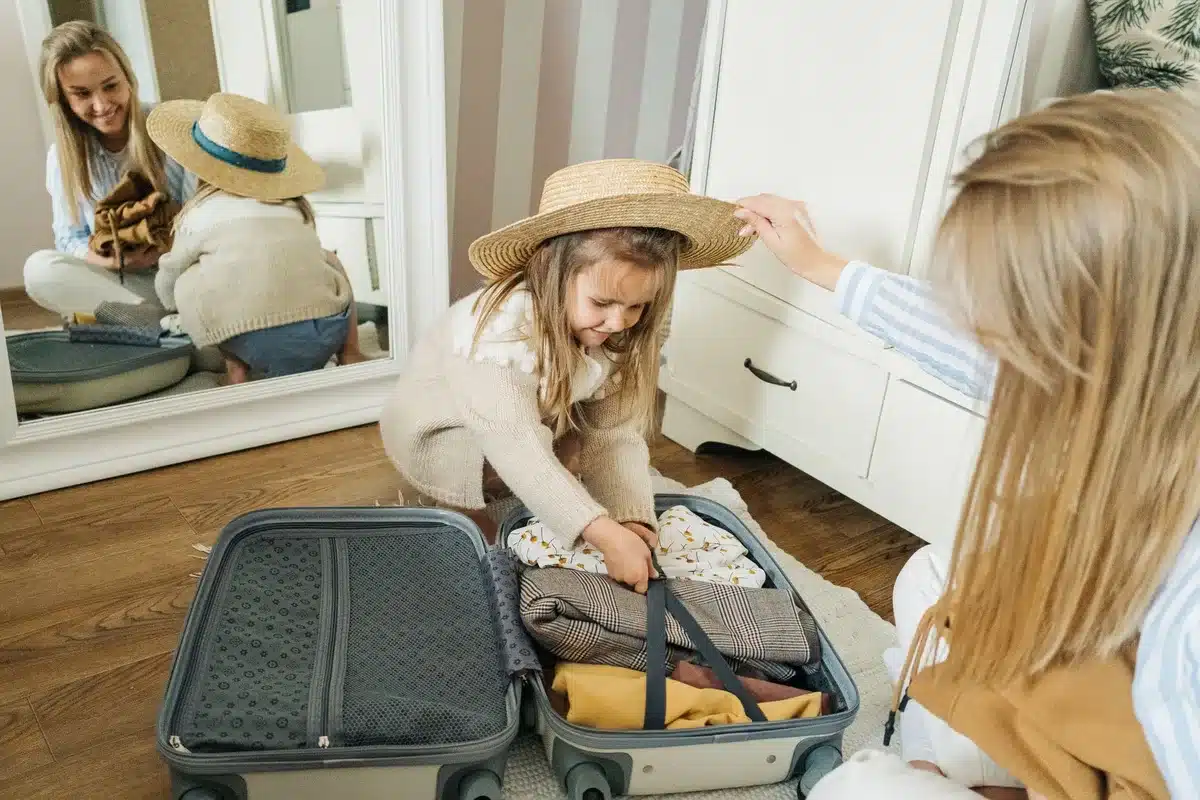 Valise ouverte avec vêtements, imperméable et accessoires de plage préparés pour les vacances