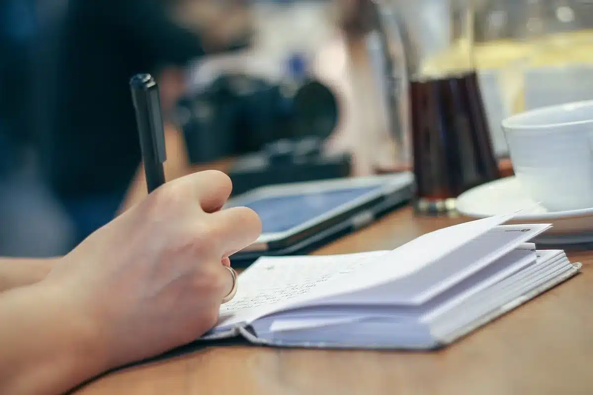 Personne écrivant des questions ouvertes dans un carnet avec concentration
