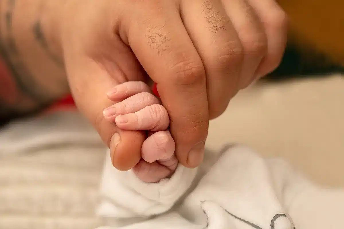 Main d'un parent tenant celle d'un bébé près d'une fenêtre ensoleillée