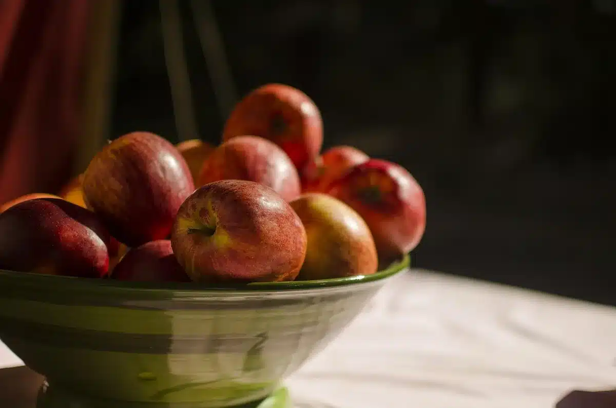 Mains préparant la pâte à crumble dans un bol avec des pommes coupées à côté