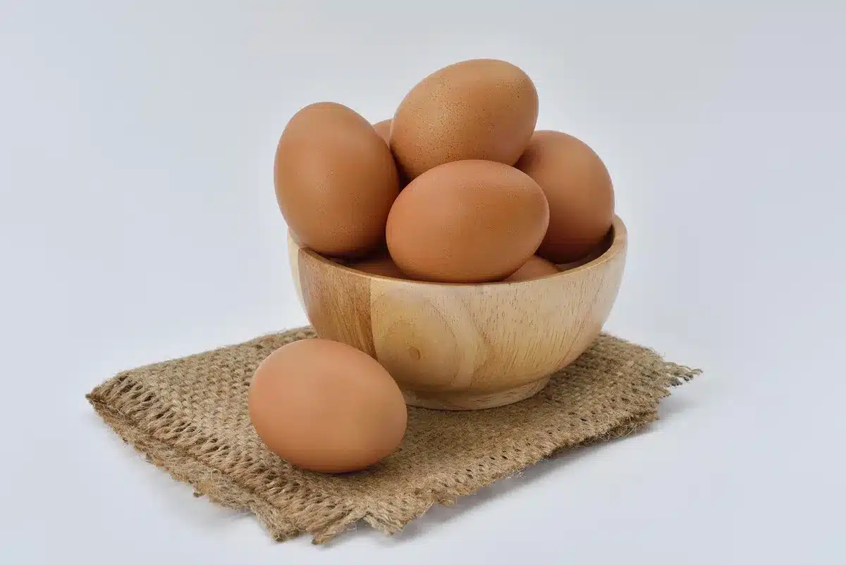 Bols et mains qui battent des œufs dans une cuisine en plein jour