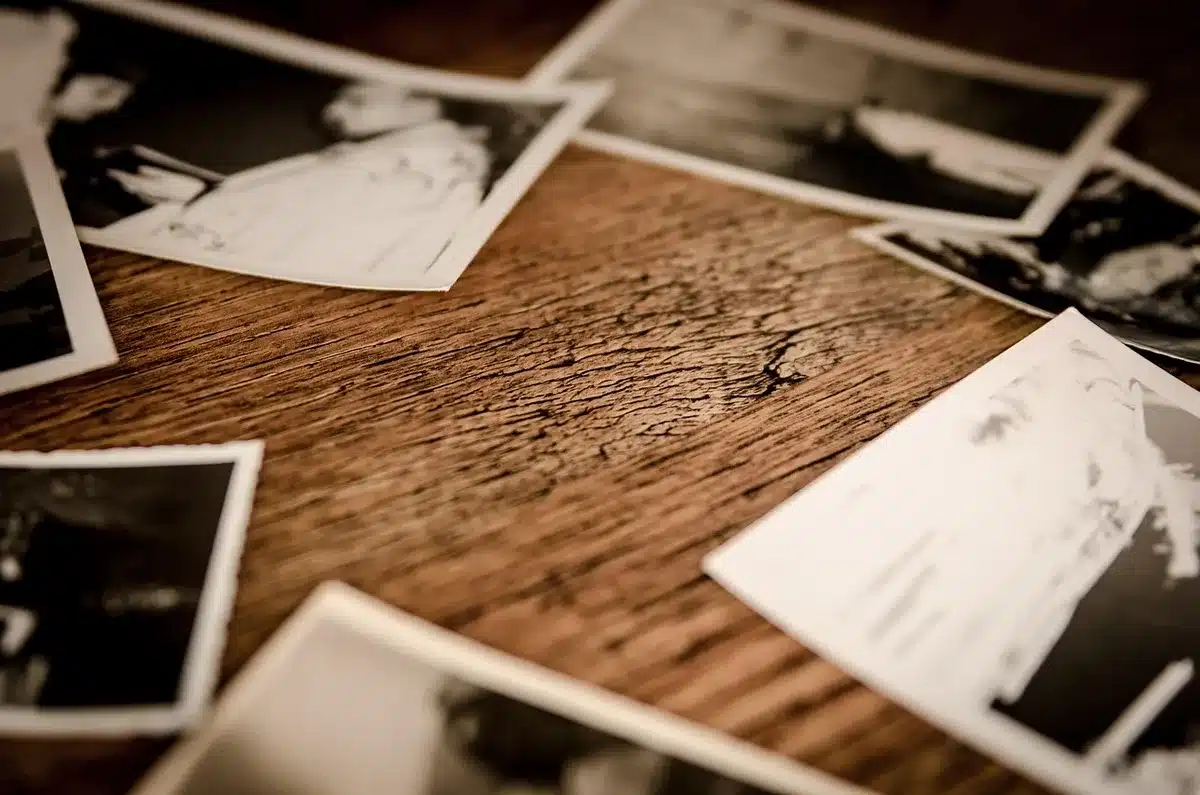 Groupe de mains feuilletant un album photo familial sur une table