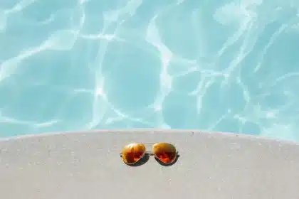 Bord de piscine en plein jour avec bâche pliée et petit coffret électrique sur une table d'équipement