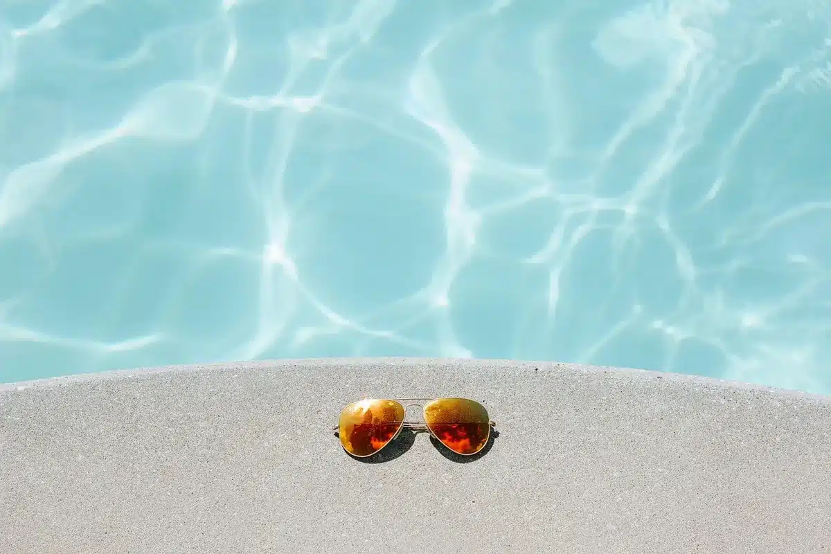 Bord de piscine en plein jour avec bâche pliée et petit coffret électrique sur une table d'équipement